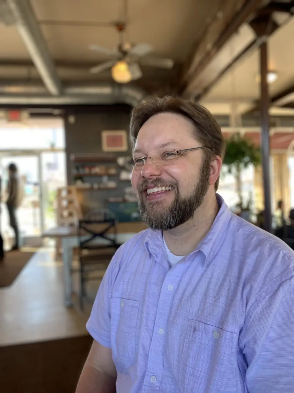 headshot of rafael in a button up smiling in a cafe